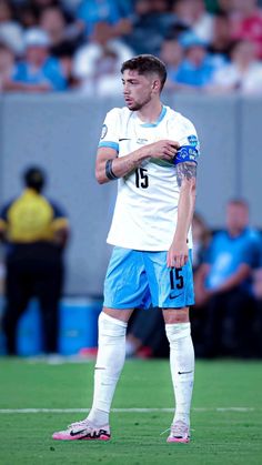 a soccer player standing on the field with his hands clasped to his chest and looking down