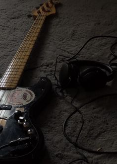 an electric guitar laying on the ground next to headphones