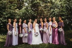 a group of women standing next to each other in front of some trees and bushes