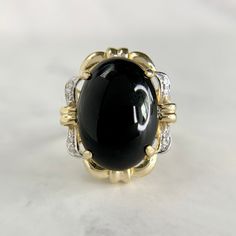 Unique Onyx cabochon ring made from 14K two-tone gold. Big look on the finger featuring accent diamonds and a stylish Japanese inspired setting. No issues to note. Stone is secure with no scuffs or abrasions. Matching earrings are available at our shop. Please contact us directly for special pricing if purchased together. We are a brick and mortar store located in Alhambra, CA. All items are guaranteed as described. SPECIFICATIONS: Ring Size: 7.75 Onyx Measurement: 17.7mm x 13mm Top Measurement: 22.2mm x 19mm Diamonds: .08ctw / Round Cut Weight: 5.98 Grams   This ring has been inspected by professionals with over 35 years of experience to ensure its excellent condition. **Please inquire about sizing before purchase or making an offer. Order will ship within 24 hours. We offer a 14-day, no- Heirloom Black Ring With Cabochon, Black Cabochon Ring In 14k Gold, Black 14k Gold Cabochon Ring, Black Cabochon 14k Gold Rings, 14k Gold Black Cabochon Rings, Formal Black Cabochon Rings, Cabochon Ring, Brick And Mortar, Statement Ring