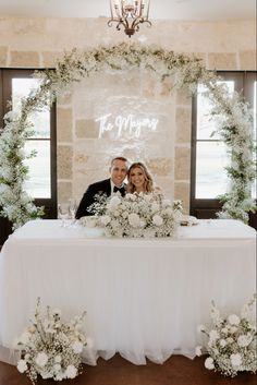 a bride and groom sitting at a table in front of a sign that says it's married