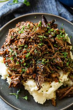 a plate with mashed potatoes topped with shredded beef and garnished with parsley