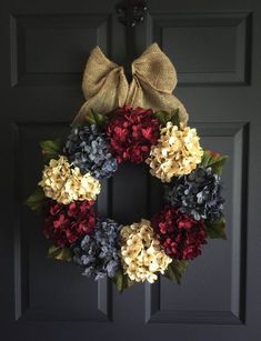 a wreath with red, yellow and blue flowers is hanging on the front door handle