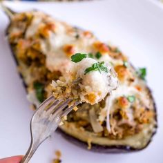 someone is holding a fork full of stuffed eggplant casserole on a white plate