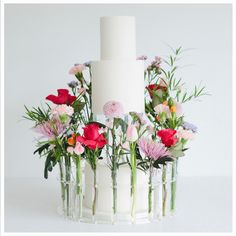 a white wedding cake with flowers in vases