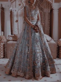 a woman in a blue and gold bridal gown standing next to a white couch