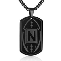 a black dog tag with the letter n on it and a football ball in the center