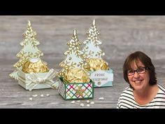 a woman sitting in front of three small christmas trees with gold foil decorations on them