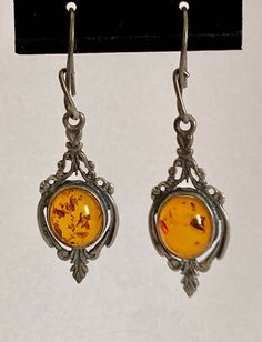 Beautiful cabochon amber set in sterling silver scrolls and frame to perfectly accent the stone. Light will shine through and highlight the inclusions.  Marked 925 Length: 1-1/3" plus hanger Width: 14.8 mm Weight: 4.5 grams / pair Your purchase supports the missions and ministries of St Paul's United Methodist Church. Oyster Bay, Old Watches, United Methodist Church, Fossil Watch, Methodist Church, Sterling Silver Charm, Silver Charms, Jewelry Earrings Dangle, Etsy Earrings