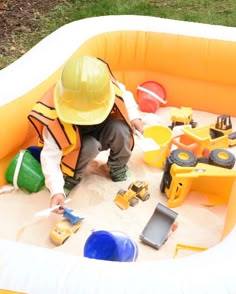 a little boy playing in an inflatable pool with construction equipment