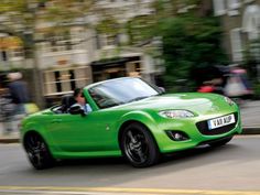 a green sports car driving down the street