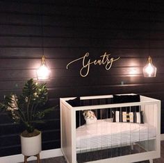 a baby crib in a room with lights on the wall and a potted plant next to it