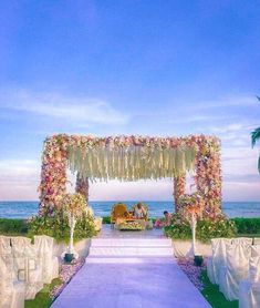 an outdoor ceremony setup with flowers and greenery on the aisle leading to the beach