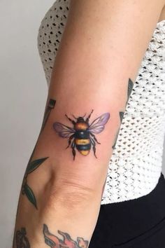 a woman's arm with a bee tattoo on it