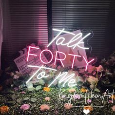 there is a neon sign that says talk forty to me on the top of some flowers