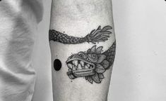 a black and white photo of a tattoo on the arm with an image of a fish