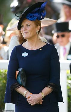 a woman in a blue dress and black hat standing next to other people wearing hats