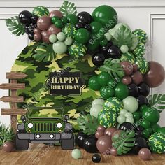 a jeep is parked in front of a jungle themed birthday balloon arch that says happy birthday