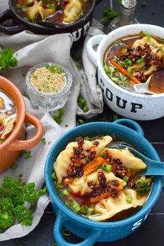 two bowls of soup with vegetables and meat in them on a table next to other dishes