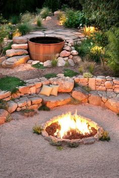 an outdoor fire pit surrounded by rocks and gravel