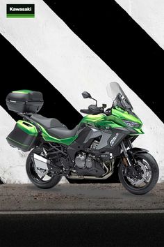 a green and black motorcycle parked in front of a white wall with the words kawasaki written on it