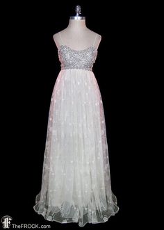 a white dress with silver sequins on the top and bottom, is displayed in front of a black background