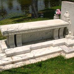 a stone bench sitting on top of a lush green field