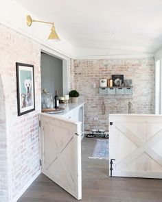 a kitchen with white brick walls and wooden sliding doors on the front door is shown