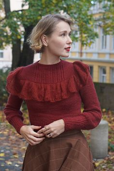 a woman wearing a red sweater and brown skirt