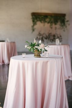 the table is covered with pink linens and white flowers