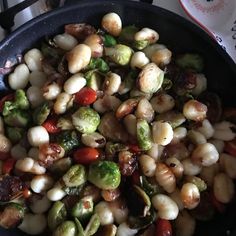 a skillet filled with vegetables and nuts on top of a stove burner next to a cup of coffee