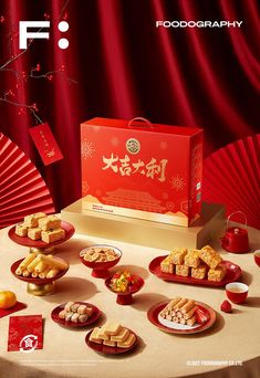 a table topped with red plates covered in food next to a red box filled with cookies