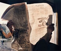 a person reading a newspaper while sitting in a chair