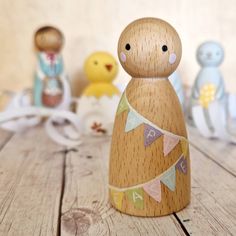 a small wooden doll with bunting flags on it's head and other toys in the background