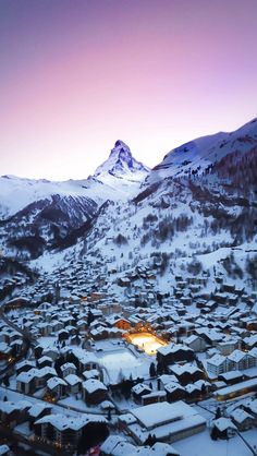 an aerial view of a snowy town with mountains in the background