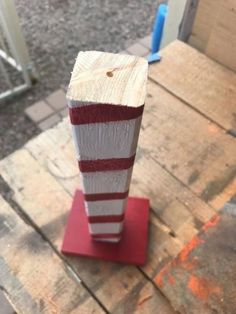 a piece of wood sitting on top of a red and white stand next to a door