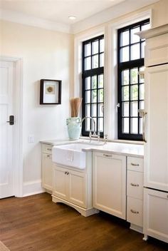 an image of a kitchen with white cabinets and black windows