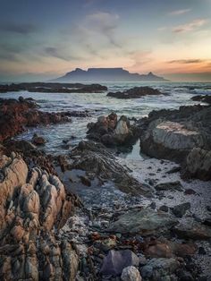 the sun is setting over some rocks and water