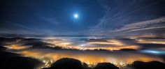 the night sky is lit up with bright lights and clouds, as seen from above