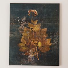 a painting hanging on the wall with flowers in it's center and yellow leaves