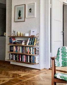 a living room filled with furniture and a book shelf next to a doorway that has pictures on the wall