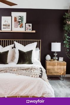 a bedroom with black walls, white bedding and pictures on the wall above it