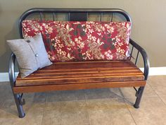 a wooden bench with a pillow on top of it next to a gray wall and tile floor