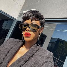 a woman with sunglasses and lipstick on her face is standing in front of a building