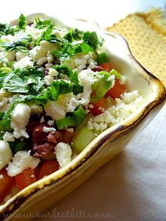 a salad with tomatoes, lettuce and feta cheese in a yellow dish