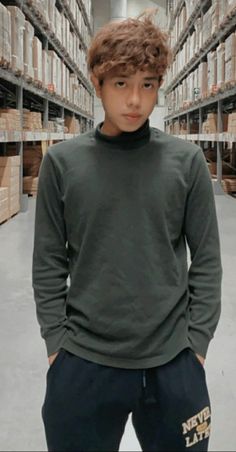 a young man standing in a warehouse with his hands on his hips