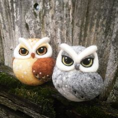 two stuffed owls sitting on top of a wooden fence