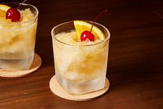 two glasses filled with drinks sitting on top of a wooden table