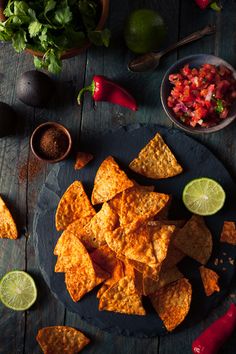 tortilla chips on a plate with salsa and limes