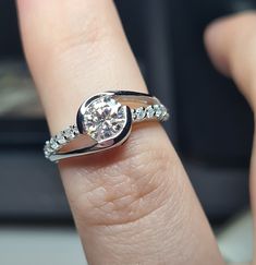 a woman's hand with a diamond ring on top of her finger, showing the center stone